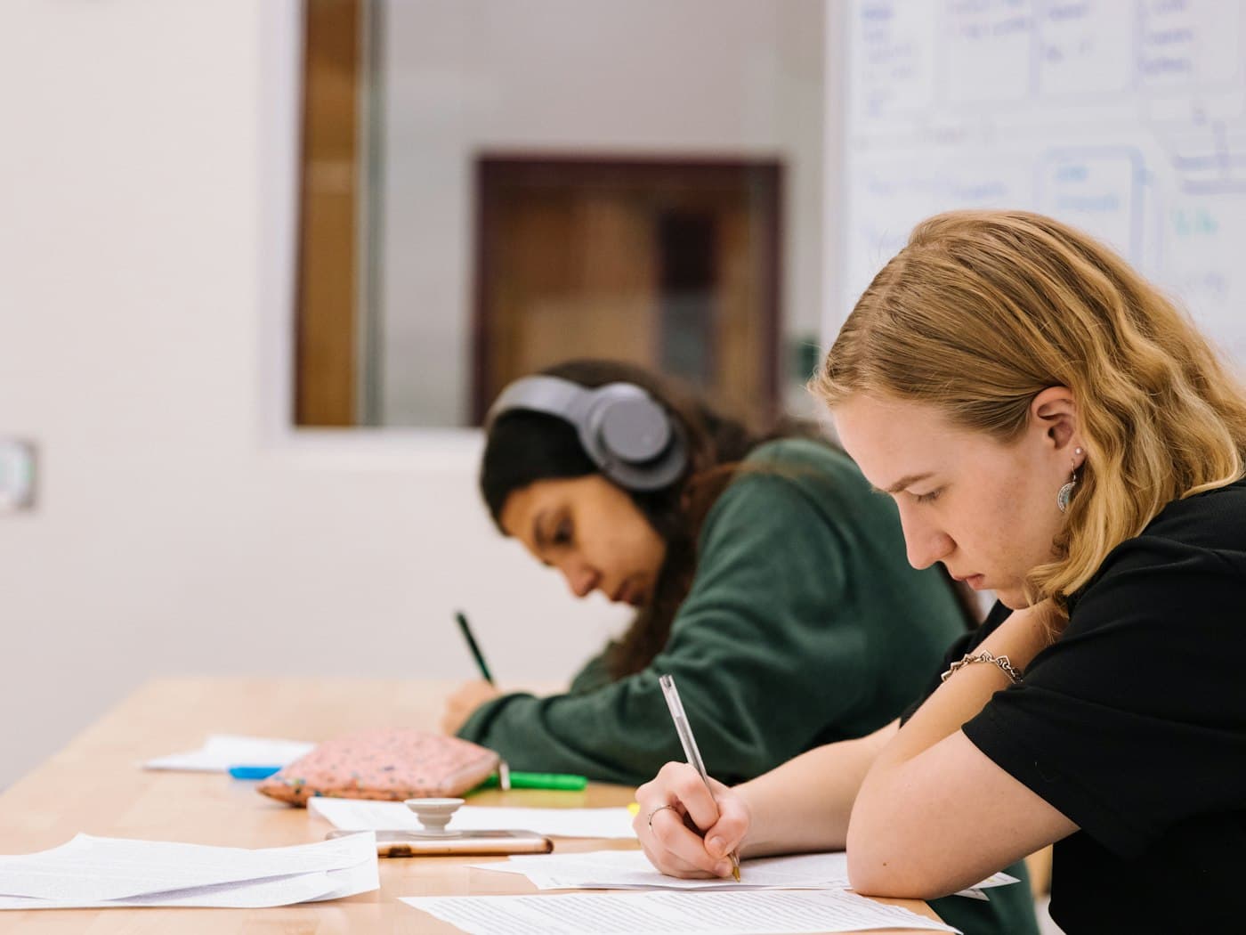 Two students writing answers at a desk
