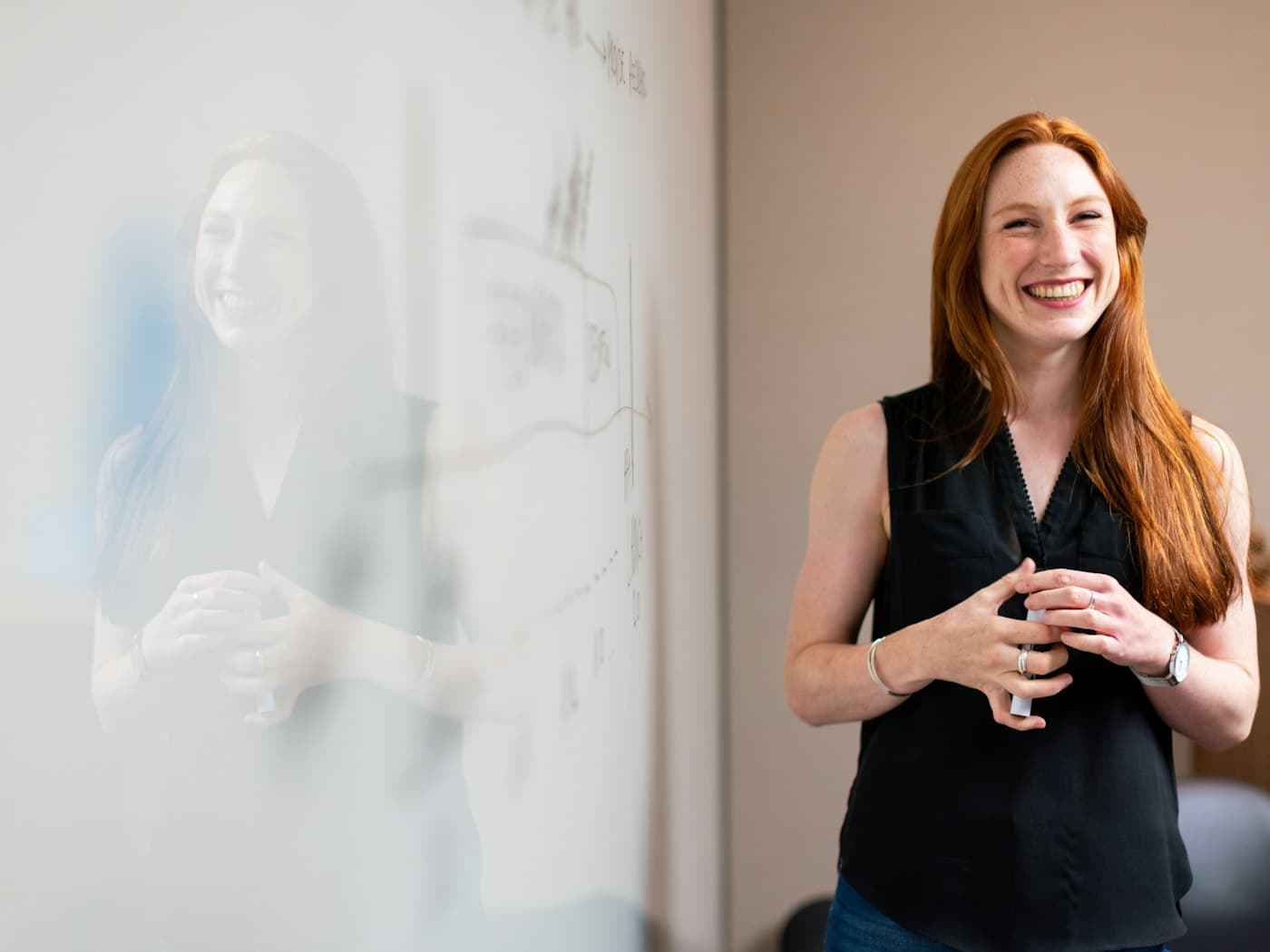 A teacher smiling in front of a whiteboard