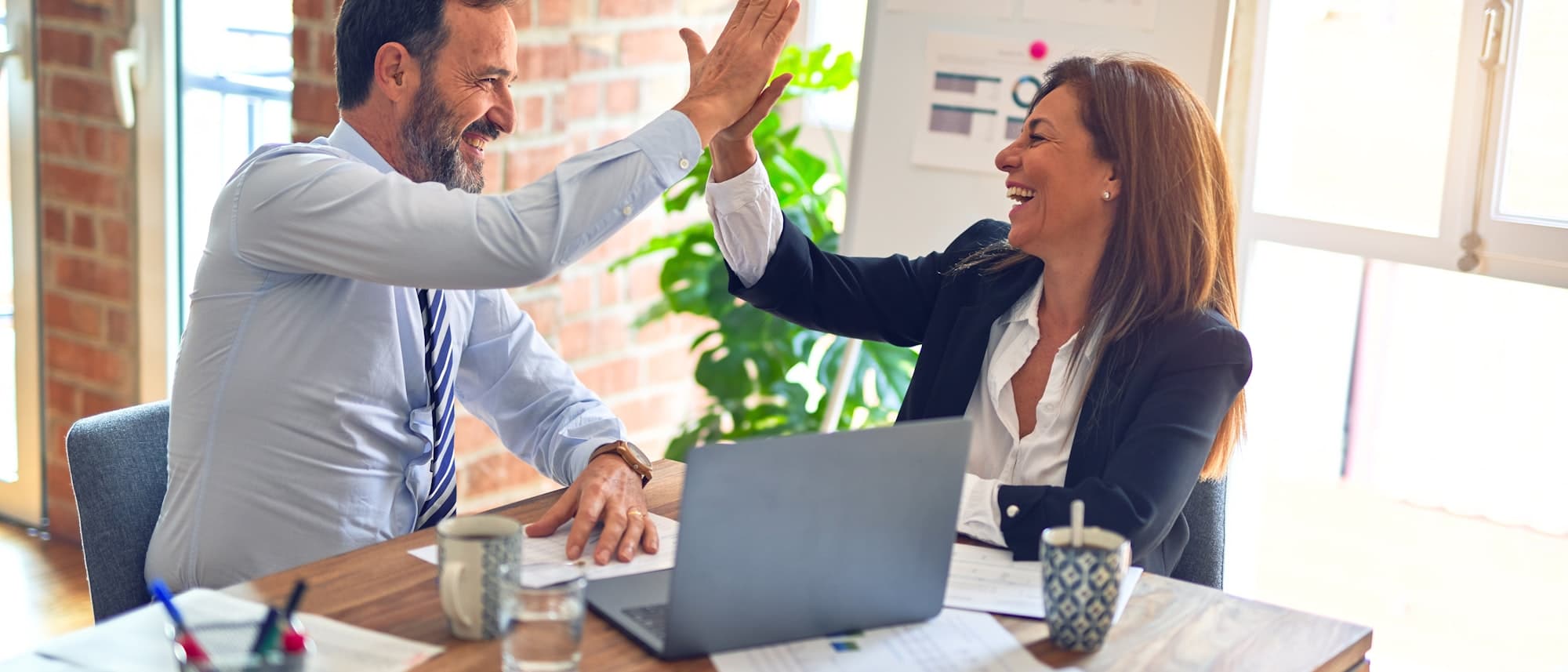 Two teachers celebrating a set of results at a desk